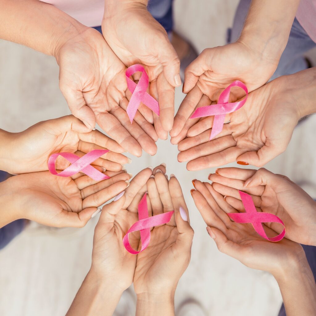 Female Hands Joined In Circle Holding Pink Ribbons, White Background