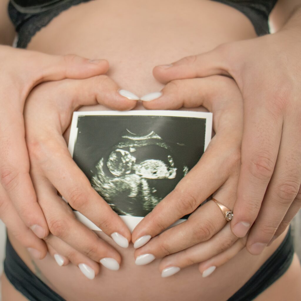 Close up cropped of couple showing ultrasound picture scan of baby, family expecting first baby